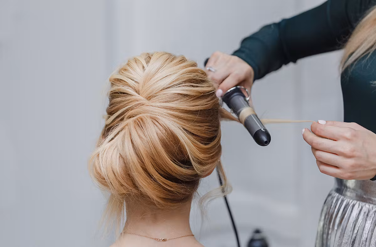 Hochsteckfrisur bei Address Beauty in Leverkusen wird mit dem Lockenstab nachgearbeitet