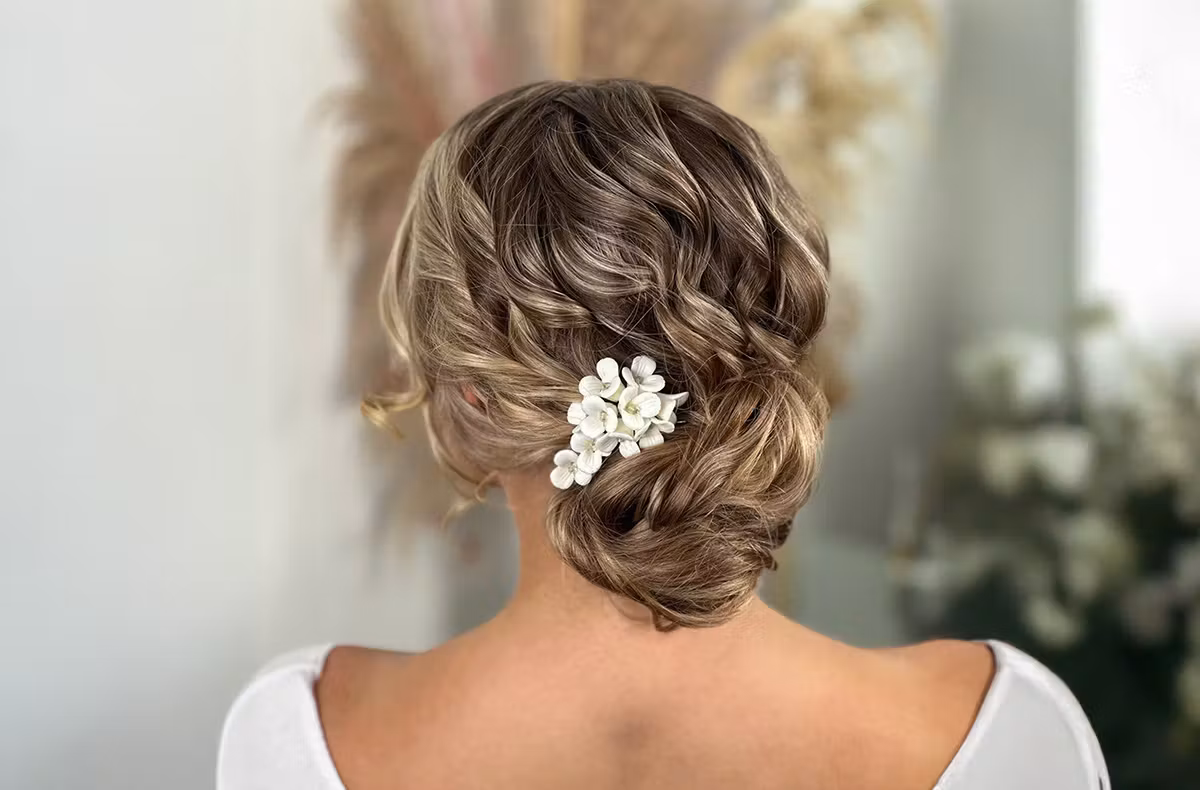 Brautstyling bei Address Beauty in Leverkusen: lockerer Chignon im Nacken mit weissem Blumenschmuck