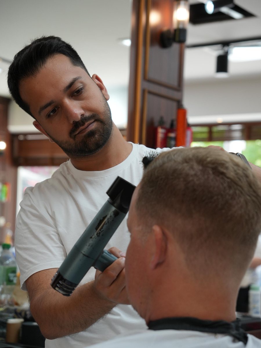 Alim, Barber im Murat Türkan Barber Salon, föhnt einen Haarschnitt aus